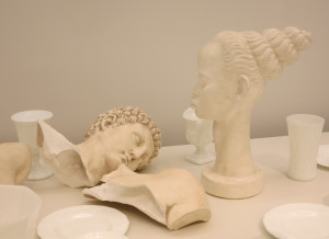 Fred Wilson, Love and Loss in the Milky Way (seen in detail), 1 table with 47 milk glass elements, 1 plaster bust, 1 plaster head, 1 standing woman and a ceramic cookie far, 77 ¾ x 92 x 43 7/8 inches, 2005.